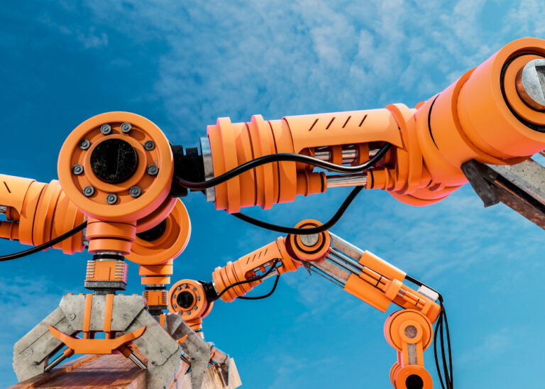 A close-up view of several large, orange robotic arms with mechanical joints and cables, set against a blue sky with some clouds.