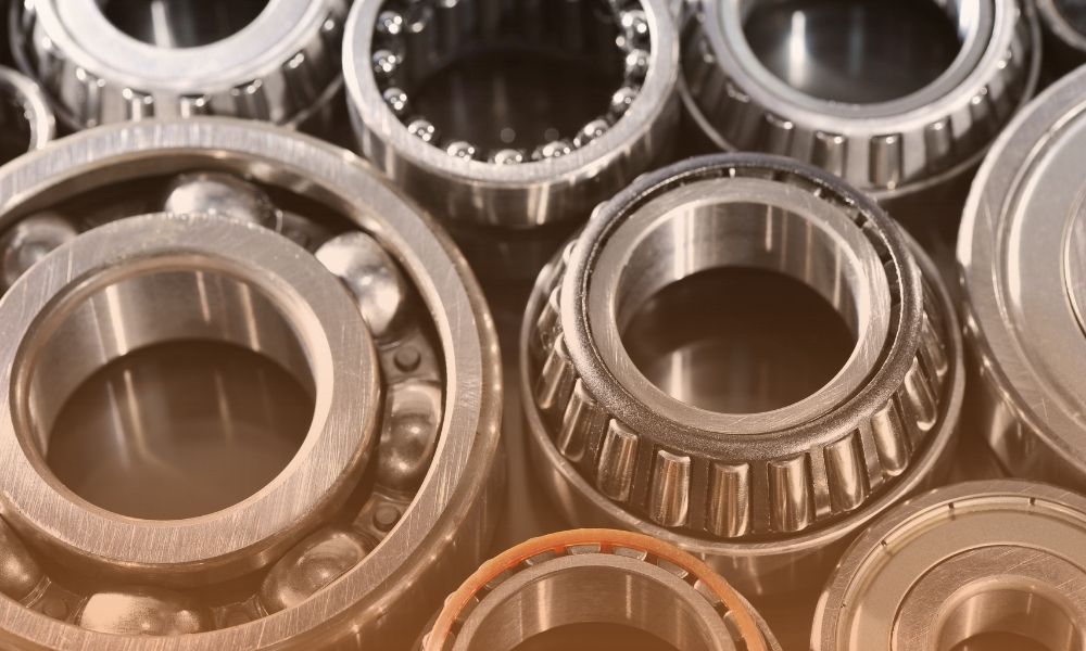 A close-up view of various metallic ball bearings and roller bearings, showing their circular shapes and inner and outer rings, arranged together in an industrial setting.