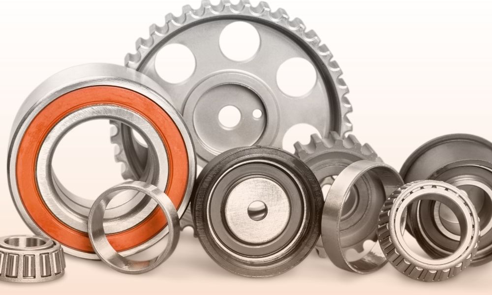 A collection of various metal and plastic gears and bearings arranged on a neutral background, showcasing different sizes, shapes, and designs used in mechanical and industrial applications.